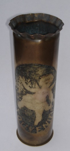 Shell depicting a playful Cupid in a medallion including word SOUVENIR, surrounded by a garland of flowers. Blackened background.