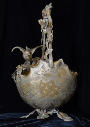 Metal basket with scalloped rim, bird perched on the rim. Outside decoration of silver and gold tones leaves and&nbsp; speckled patterns.