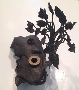 11lb of debris&nbsp; from ordnance transformed into an inkstand with pen holder, snake curled, vertical branches of leaves as background.