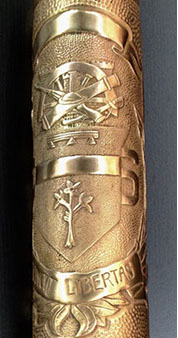 Escutcheon with three-pronged heraldic emblem. Below sapling with&nbsp; thirteen leaves. Banner VINCIT LIBERTAS, 7 and 6, garland.