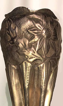 Detail of the bulbous top and the indentation work under the embossed daisies.
