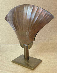 Two pieces of ordnance debris shaped as sea shells soldered togther on a stemmed stand