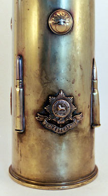 Shell with badges as the Worcestershire Regiment, cartridges soldered, and small flaming bombs
