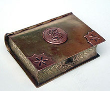Jewel box in the shape of a book. Lid with center medallion in copper. Two edges&nbsp; with&nbsp; copper&nbsp; flower.